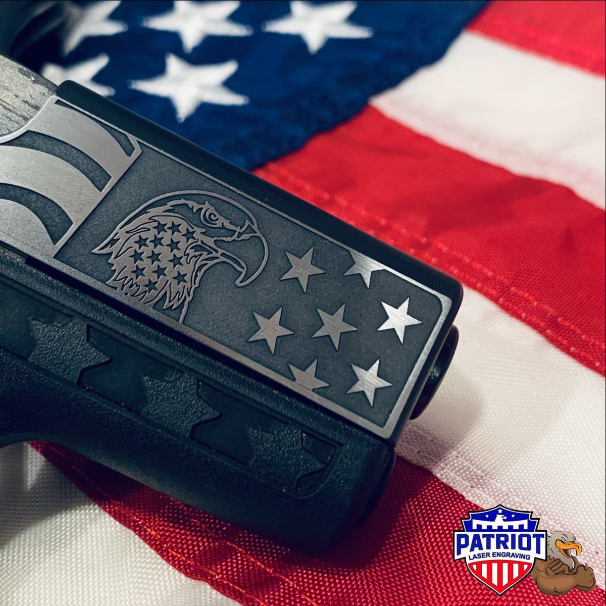 A photo of a deep engraved glock slide with an eagle and stars and stripes shown at an angle with a US Flag in the background.