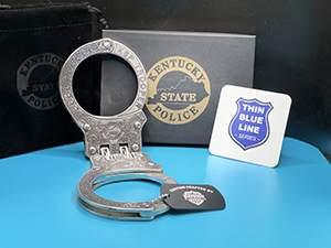 A photo of a pair of deep engraved cuffs with a card containing the thin blue line series logo.