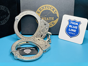 A photo of a pair of deep engraved cuffs with a card containing the thin blue line series logo.