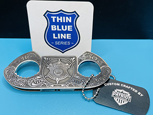 A photo of a pair of deep engraved cuffs with a card containing the thin blue line series logo.