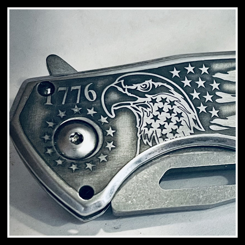 A photo of a deep engraved pocket knife with the numbers 1776 stars and stripes, and an eagle. A patriotic version of an engraved pocket knife.